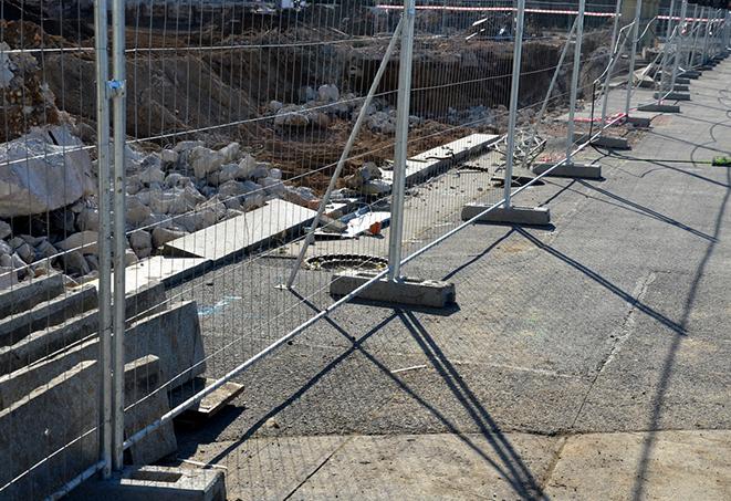 a row of sturdy temporary fence panels separating a construction site from surrounding areas